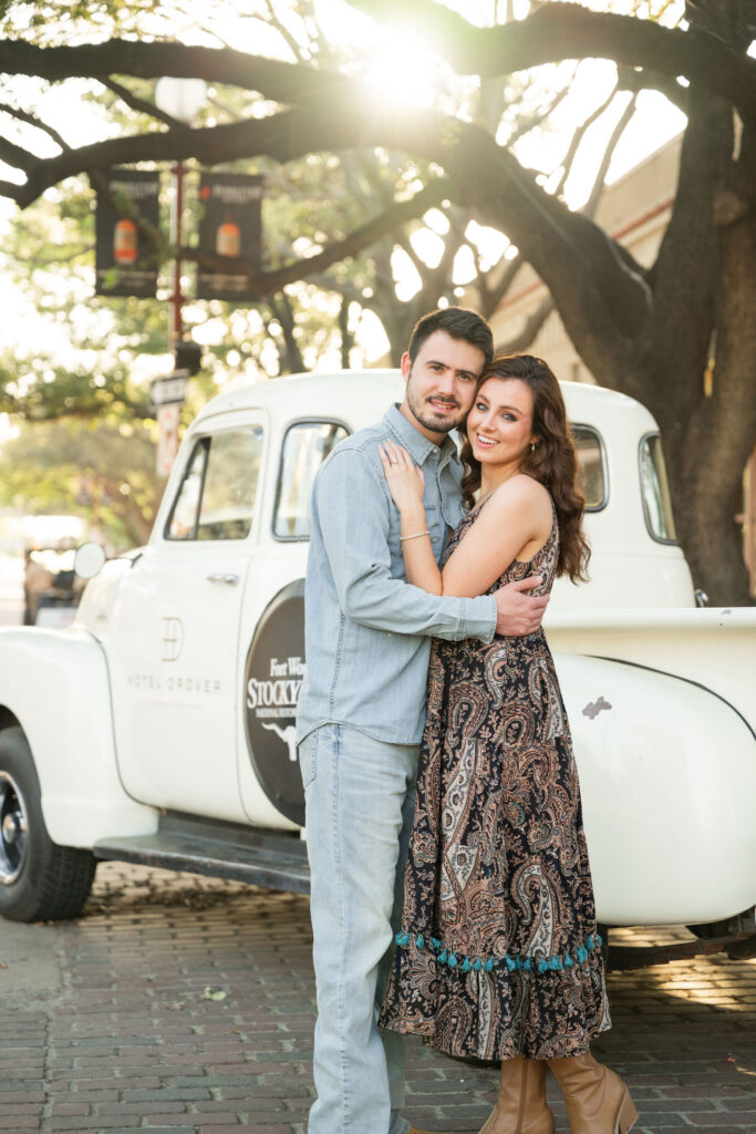 Couple embracing beside a vintage white truck at the Fort Worth Stockyards