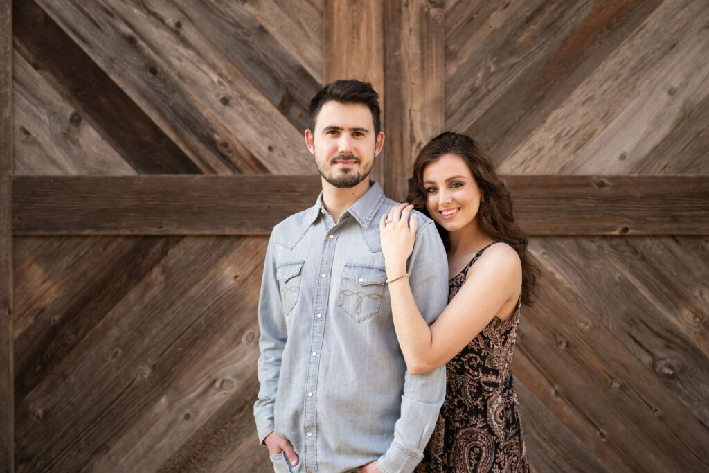 Couple posing in front of rustic wooden barn doors at the Fort Worth Stockyards