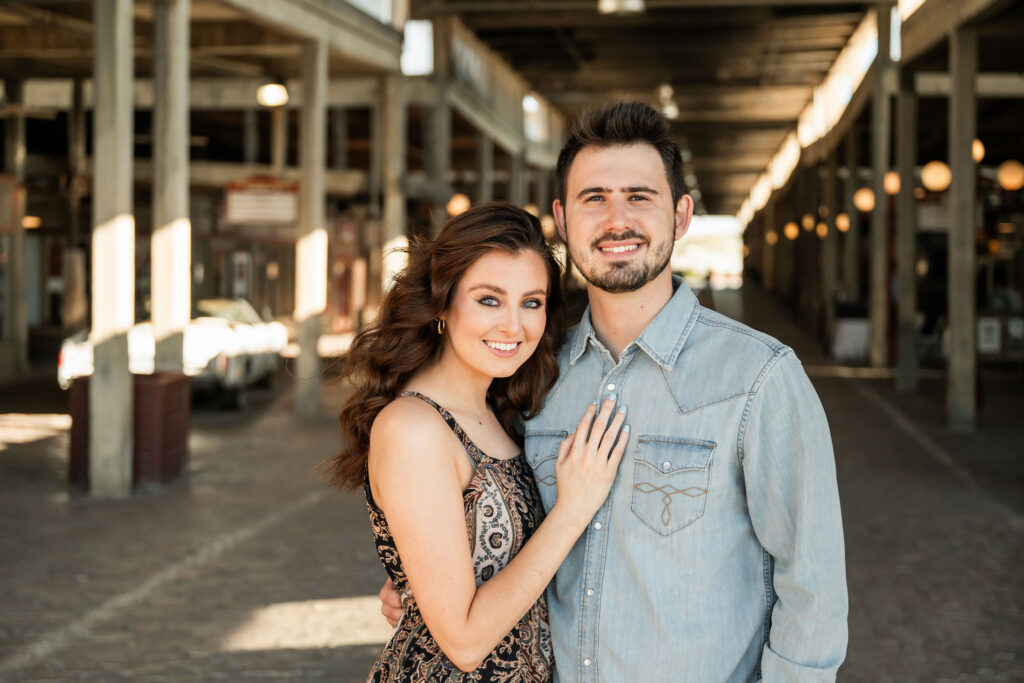 Smiling couple posing beneath a covered walkway at the Fort Worth Stockyards