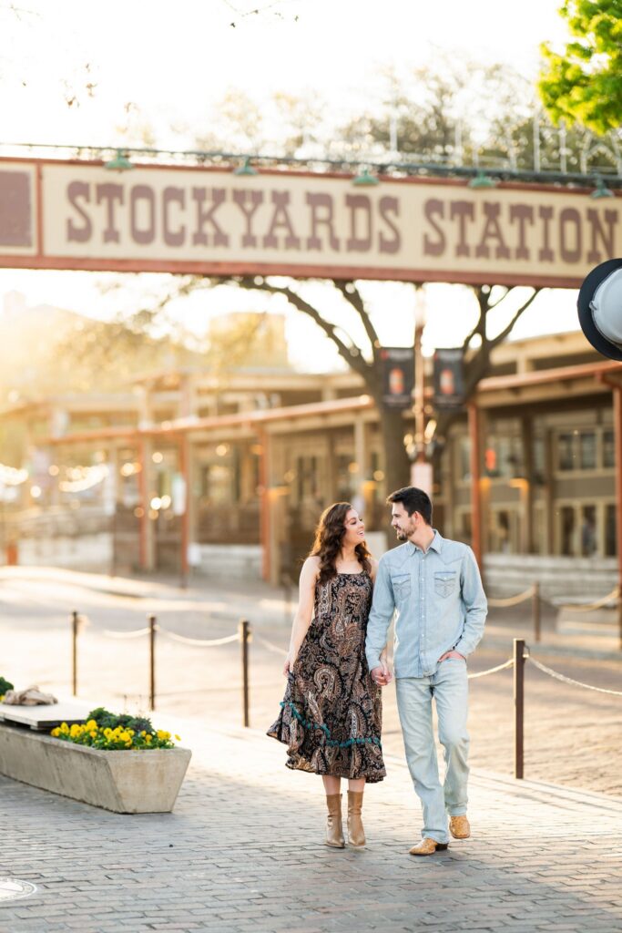 Couple walking beneath the Stockyards Station sign during a sunrise session in Fort Worth