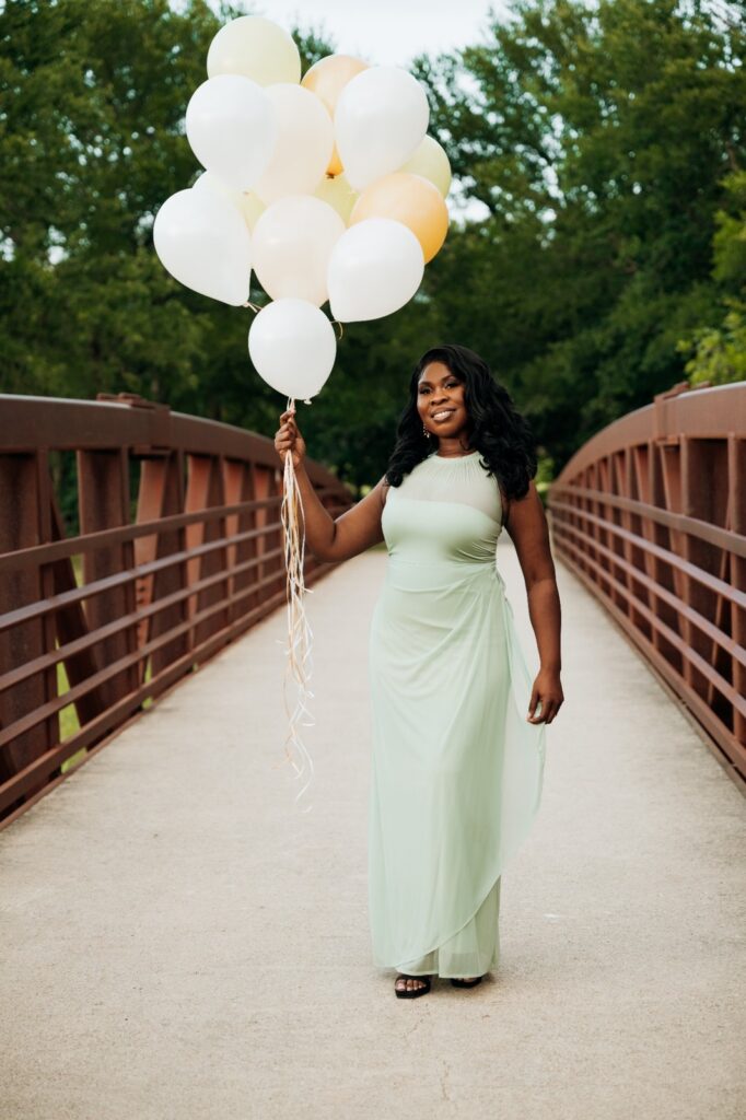 Woman celebrating her birthday with balloons on a bridge at Keller Pointe