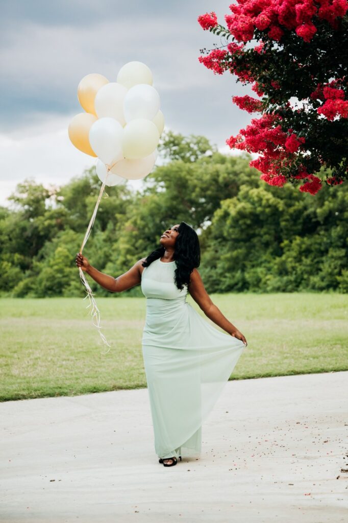 Woman in a mint-green dress posing with birthday balloons in Keller